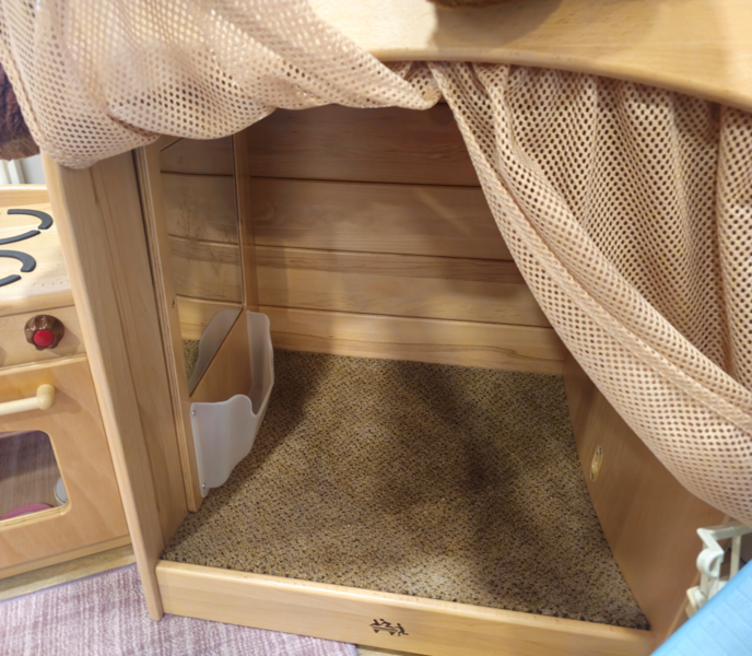 Inside a cosy nook, with a soft carpeted base, mirror and mesh curtain drawn back