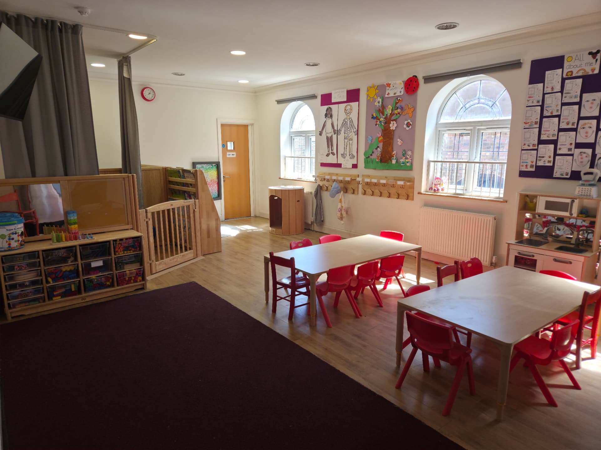 Red Room main learning area with tables, construction resources and role-play kitchen