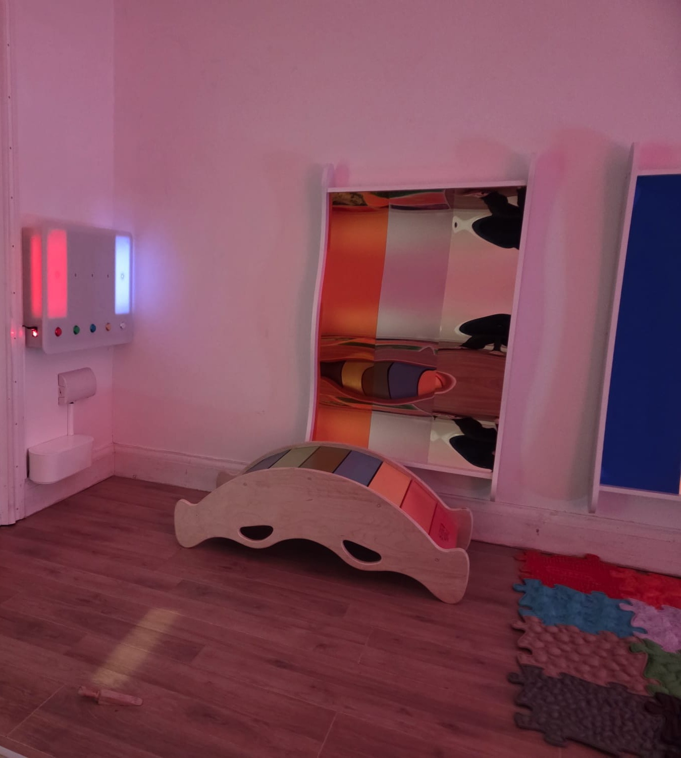 A wooden rocker, distortion mirror panels and textured mats in a softly lit calm area